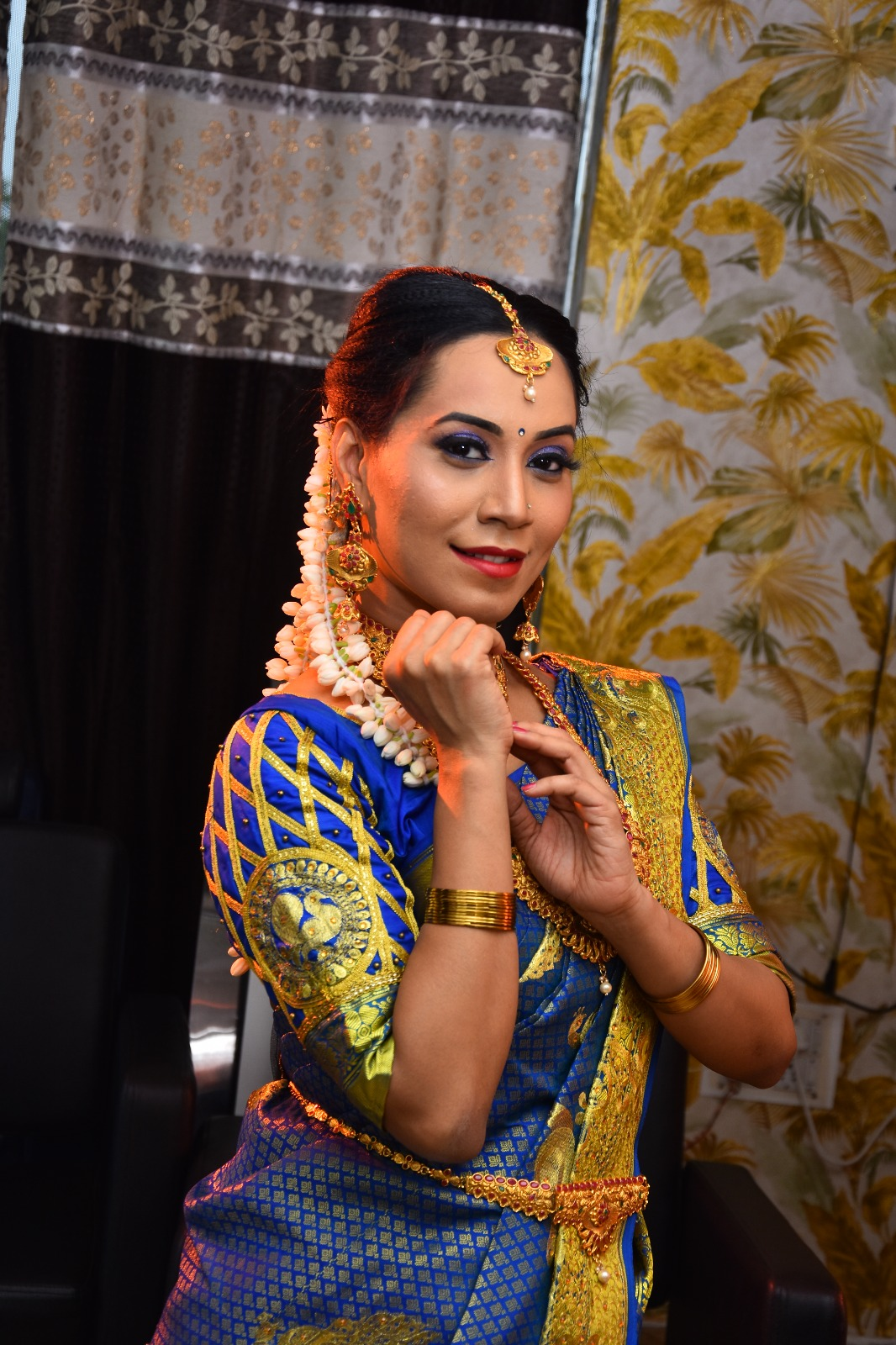 South Indian bride in a royal blue and gold silk saree with traditional gold jewellery, jasmine flowers, and elegant bridal makeup